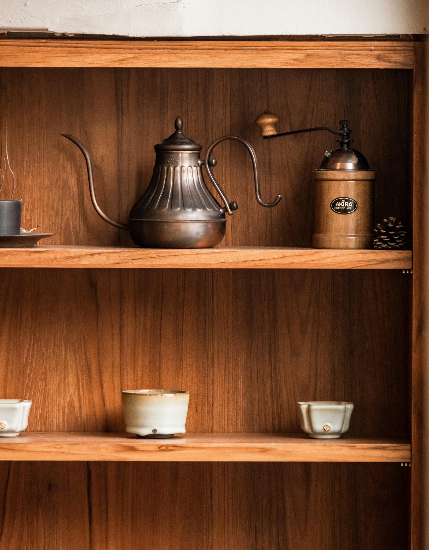 Cupboard holding silver kettle, coffee  press and various serve and drinkware 
